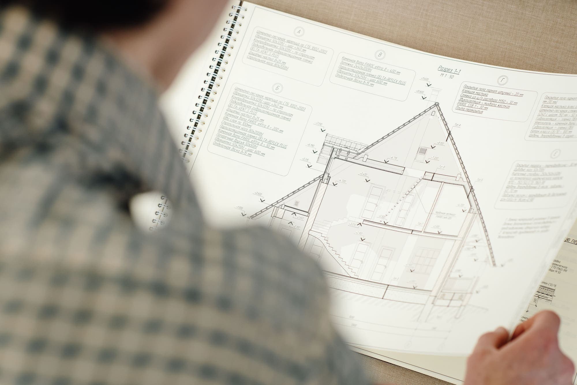 Persoană analizând planul secțiune al unei construcții, cu detalii tehnice și cote